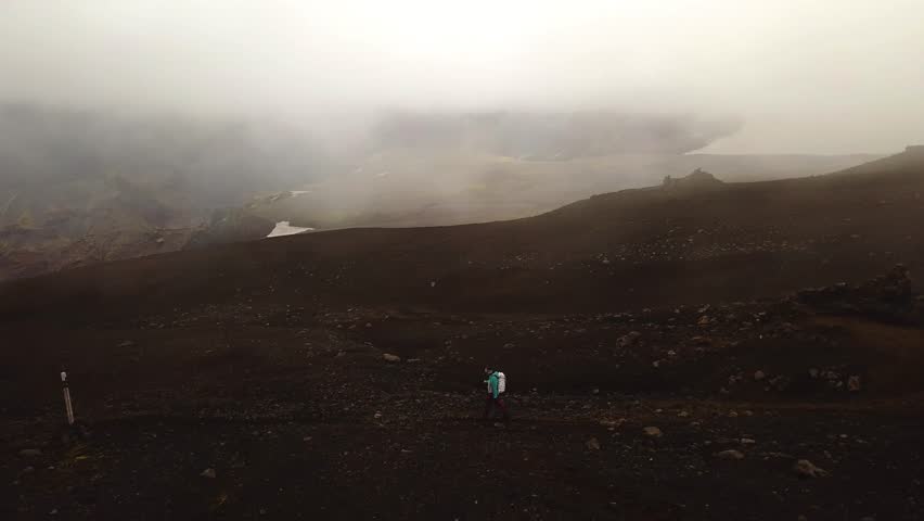 Aerial panoramic view of a person hiking on a mountain trail, on a foggy day, Fimmvörðuháls area, Iceland