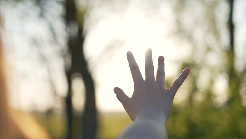 Happy girl stretches her hands to sun. Children palm in rays of sun at sunset.Young woman raising her hands praying at sunset or sunrise.Freedom in nature and spirituality concept.Fingertips touch sun Royalty-Free Stock Footage #1100360197