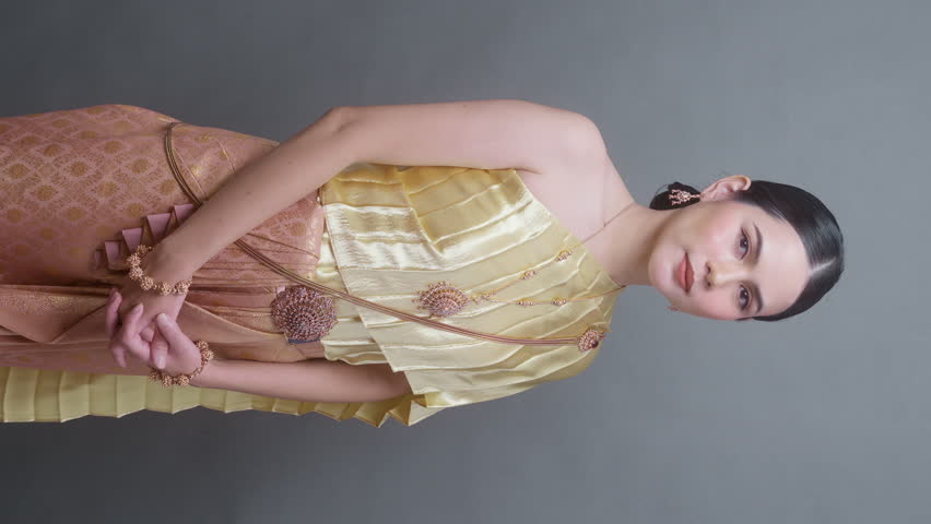 Vertical video. A young asian woman wearing Thai traditional cloth on gray background