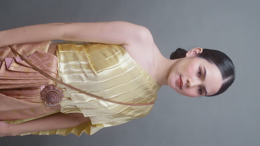 Vertical video. A young asian woman wearing Thai traditional cloth on gray background