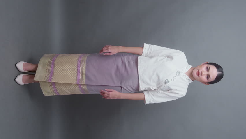 Vertical video . A young asian woman wearing Thai northern traditional cloth on gray background
