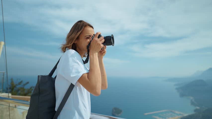 attractive woman hipster travel blogger takes photo on professional camera, viewpoint among mountains and blue sky, cableway destination. viewpoint of Tunektepe Teleferik, Antalya, Turkey