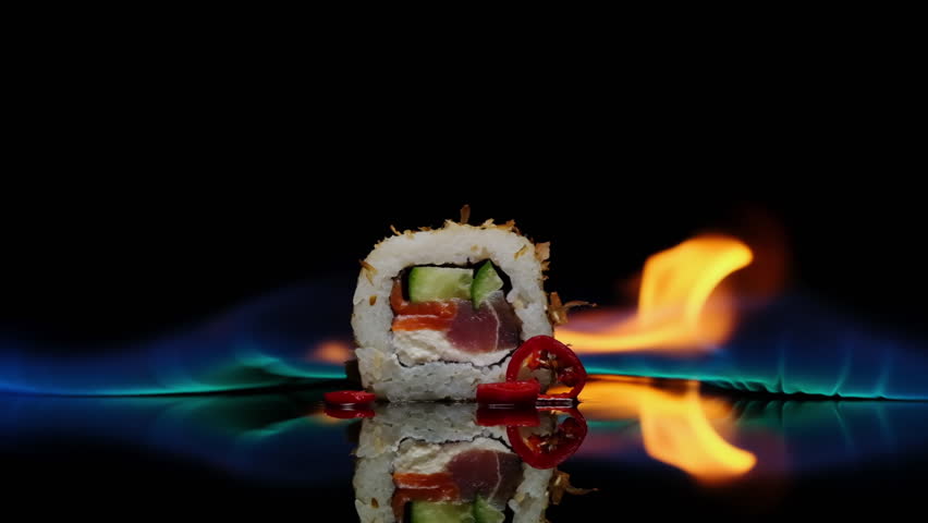Spicy sushi roll burning with flames rotates on black background on mirrored reflective table close-up. Sushi menu, Japanese food, Asian cuisine. | Shutterstock HD Video #1100365453