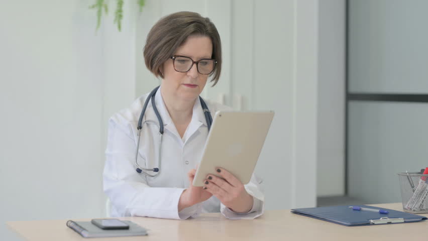 Senior Female Doctor Browsing Tablet in Clinic | Shutterstock HD Video #1100367273