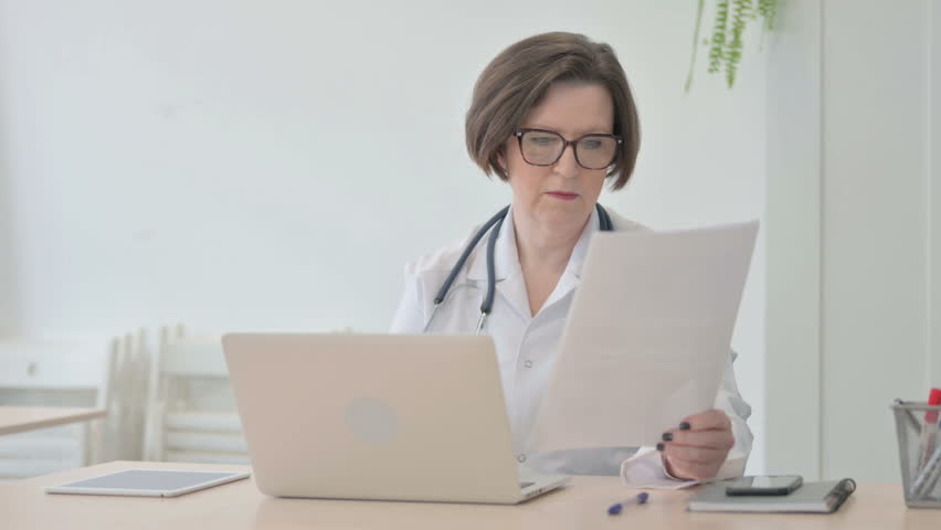 Old Senior Doctor Working on Documents and Laptop in Clinic | Shutterstock HD Video #1100367311