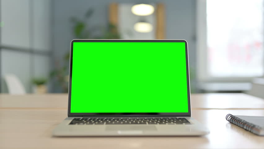 Laptop with Green Screen on Desk in Office