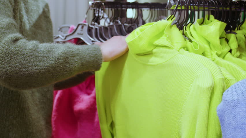 Faceless woman is shopping in clothing store. Girl is looking for turtleneck of right size in shop. Female costume designer, stylist chooses sweater for her client. Lady updates her wardrobe