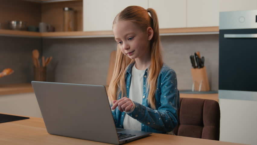 Caucasian little child girl at home kitchen using laptop educational course homework online studying teen school student kid daughter schoolgirl use computer Internet browsing distance web learning Royalty-Free Stock Footage #1100371215