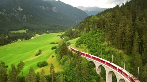 Drone Switzerland 4k. Glacier Express red swiss train in Swiss Alps. Rhaetian Railway famous Landwasser viaduct bridge. Zermatt to St. Moritz. Switzerland summer tourism. - Βίντεο στοκ
