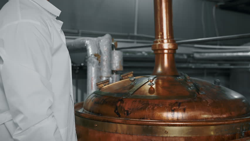 Food technologist opening copper beverage processing tank at the factory. Food industry facilities