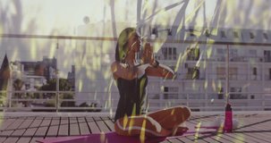Animation of plants over biracial woman practicing yoga. Health and fitness, active lifestyle concept digitally generated video.
