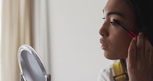 Animation of light spots over biracial woman applying mascara. Lifestyle, fashion and light concept digitally generated video.