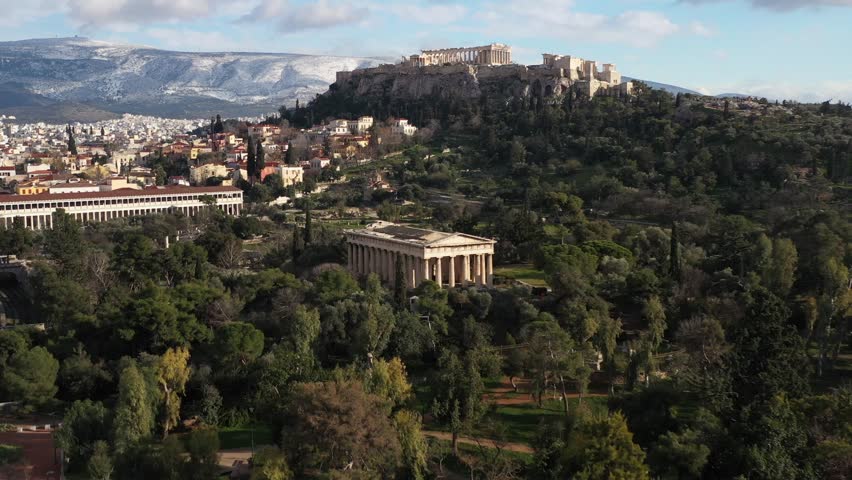 Aerial forward shot on Temple of Hephaestus with the beautiful background of Acropolis and snowy mountain view in the winter month Royalty-Free Stock Footage #1100385523