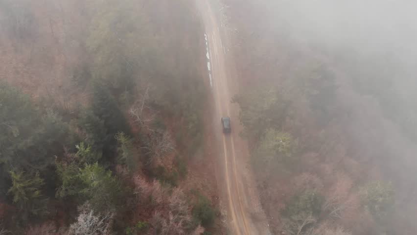 Aerial Drone Shot Tracking follow Car 4x4 foggy cloudy forest mountain
