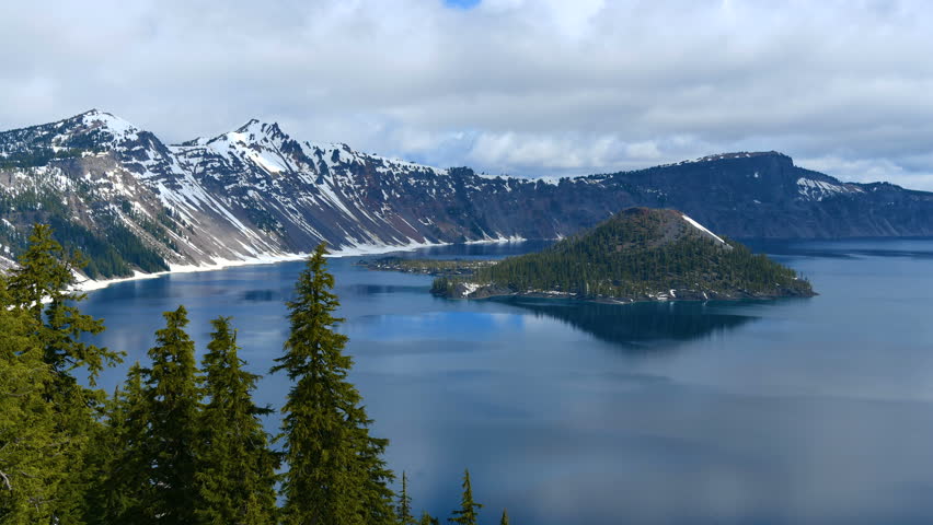 Crater Lake - A time-lapse video of low clouds passing over blue Crater Lake and rocky Wizard Island on a calm Spring morning . Crater Lake National Park, Oregon, USA.
