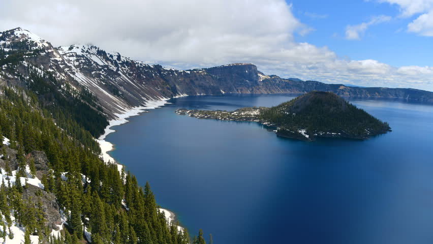 Crater Lake - A time-lapse overview of blue Crater Lake and rocky Wizard Island on a cloudy Spring morning. Crater Lake National Park, Oregon, USA.