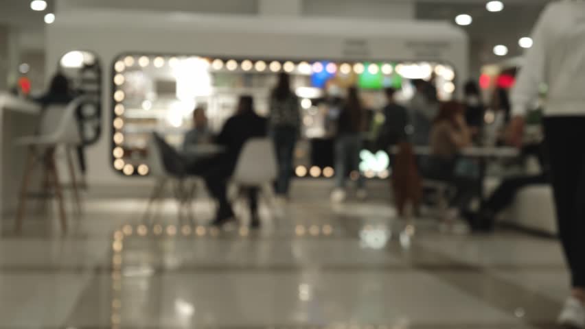 blurry footage of cafes with people drinking coffee and tourists walking by. a small cafe in a city shopping center with blurry unrecognizable people. abstract business background of urban life.