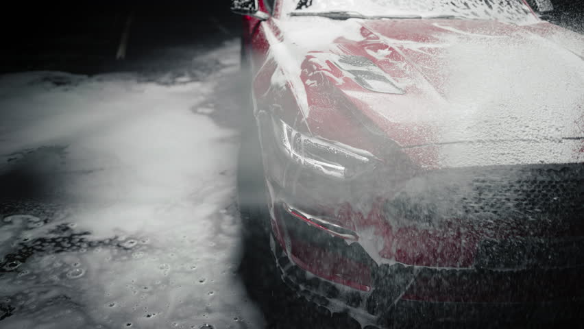 Professional Car Wash Worker Applying Smart Foam on a Hood of a Red Sportscar with Retro Design at a Dealership Car Detailing Center. Commercial Studio Footage for Automotive Advertising | Shutterstock HD Video #1100395825