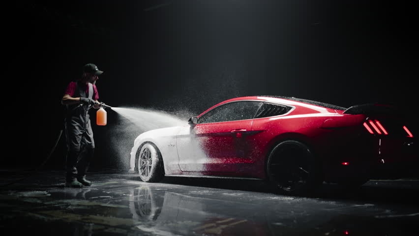 Professional Car Wash Specialist Applying Smart Foam to Prepare a Modern Red Sportscar with Retro Design for Sale at a Dealership Car Center. Commercial Studio Footage for Advertising
