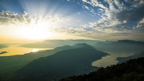 Hot summer sun illuminates shores of Adriatic Sea and slopes of Montenegrin Mountains with hotels in resort town Kotor