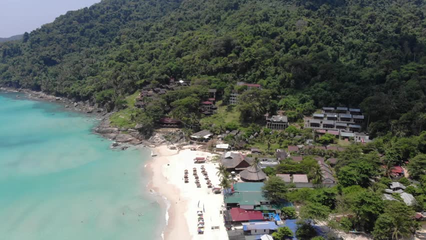 Aerial view of greenery and mountains near beach - moving right to left