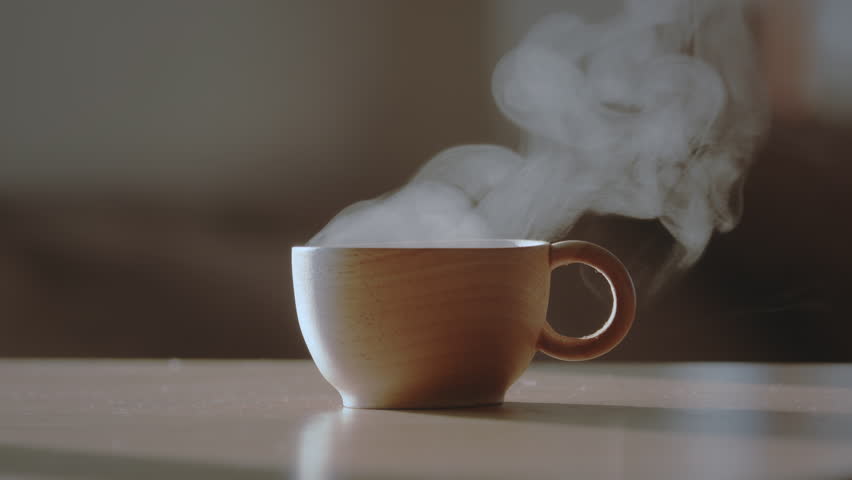 Wooden coffee cup or tea cup with natural steam smoke. Close-up of Smoke rises from cup, cup of coffee for breakfast in the morning time with warm light. Hot Coffee Drink Concept. Royalty-Free Stock Footage #1100398827