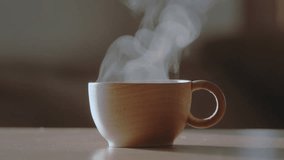 Wooden coffee cup or tea cup with natural steam smoke. Close-up of Smoke rises from cup, cup of coffee for breakfast in the morning time with warm light. Hot Coffee Drink Concept. - Powered by Shutterstock - Get 15% off with code: PIKWIZARD15
