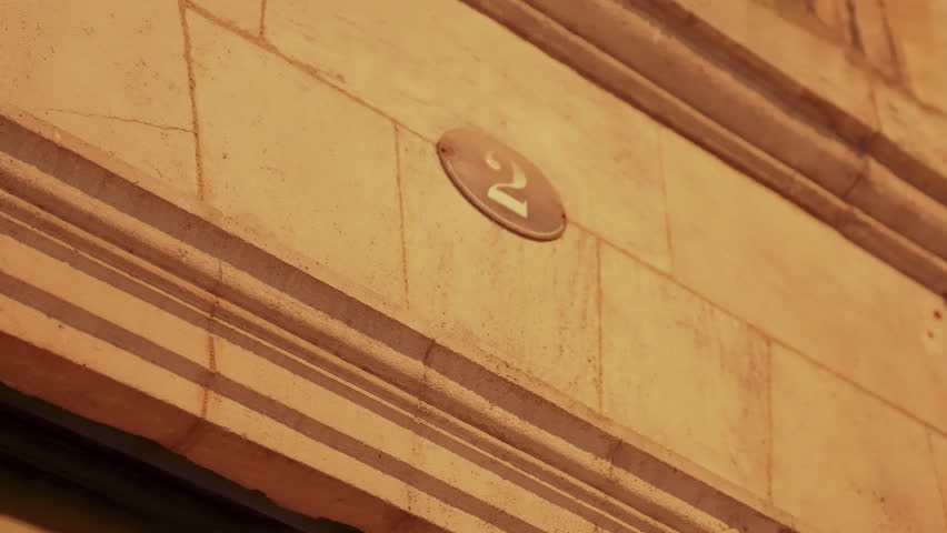 Adress number plate on top of the house entrance, Postal number 2, in dark evening lighten by street lights in Bordeaux city, slow motion