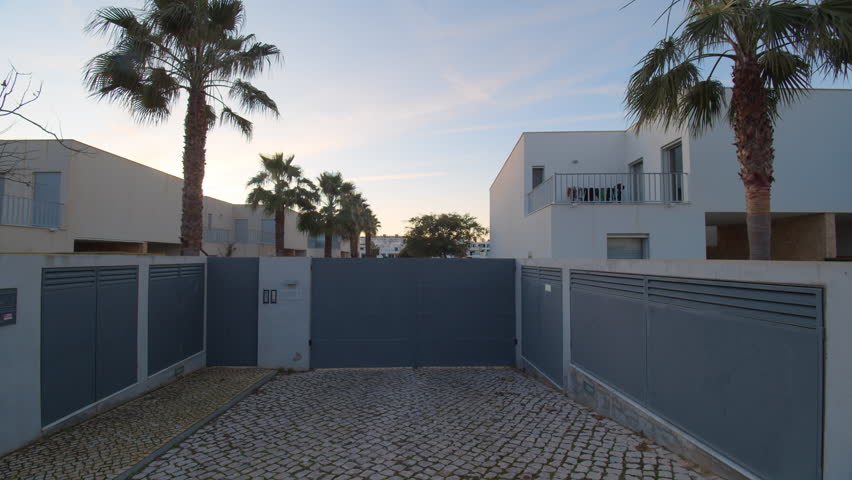 Walk through opening gates from yard to street on town at sundown
