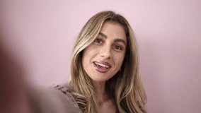 Young blonde woman smiling confident having video call over isolated pink background