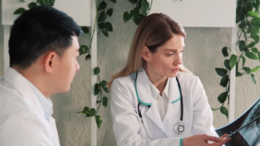 International Doctors Physicians Working, Analysing Patient X-ray, Talking about Results Analysis Health Care, Asian Chief Surgeon and Radiologist Discuss Consult about Image of Patient's Lungs. | Shutterstock HD Video #1100408857