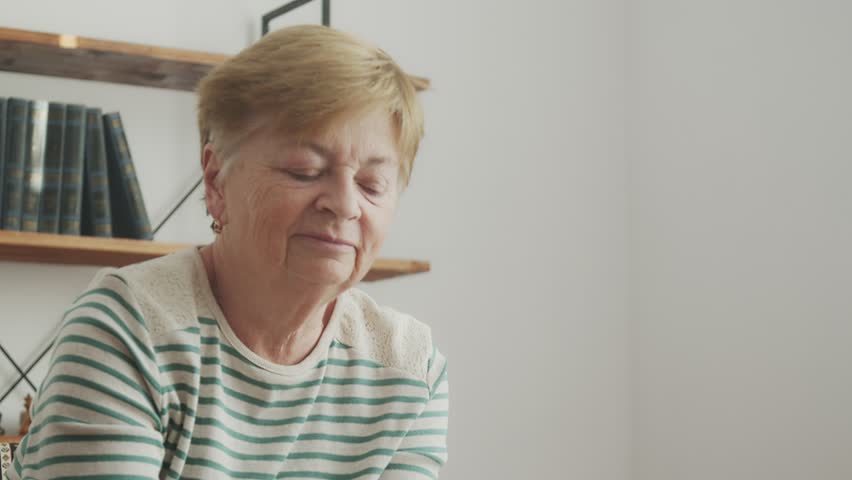 Portrait Elderly woman doing something enthusiastically and smiling. | Shutterstock HD Video #1100409377