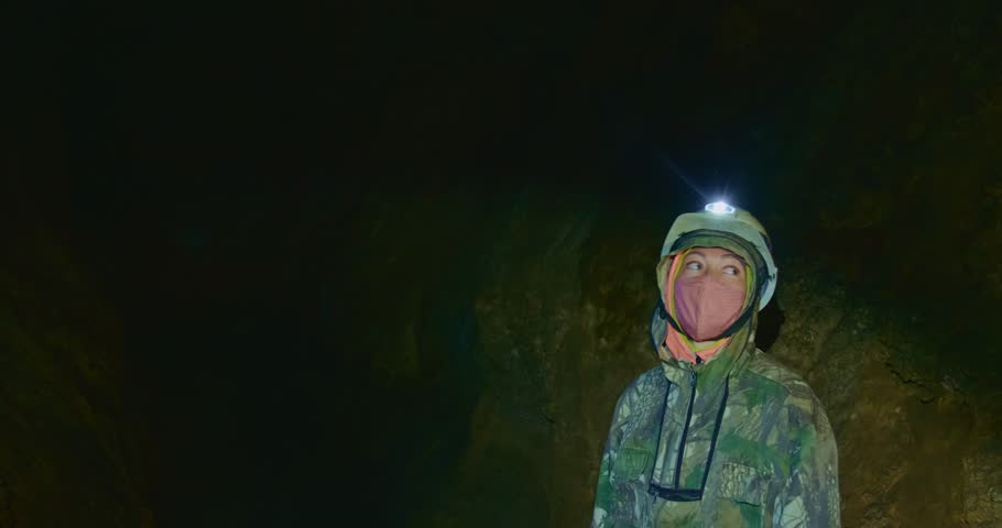 The cave excursion travel experience. The woman tourist marveled at the rock stone formations in the dark cavern. The cave tourism indoor.Its an attraction for adventure and nature lovers on any tour