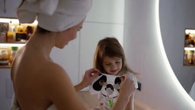 Mother applying tissue panda mask on her daughter face relaxing in the bedroom after shower - Powered by Shutterstock - Get 15% off with code: PIKWIZARD15