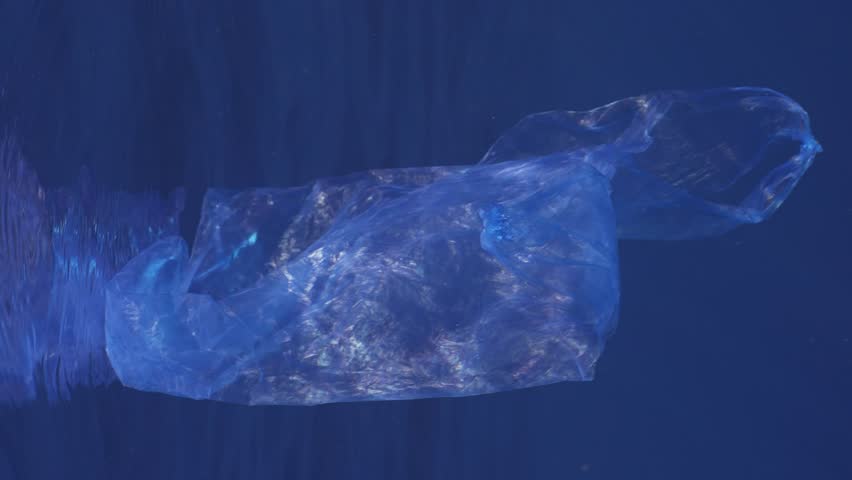 Vertical video, Plastic bag drifts in the sea under surface of water in sun light. Slow motion, Blue plastic bag thrown into the sea slowly drifts under surface of blue water in the morning sunshine  | Shutterstock HD Video #1100413729