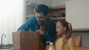 Caucasian family adult father dad with kid child girl little daughter standing in kitchen unpack paper shopping bag with food vegetables get out fresh natural products e-store delivery services online - Powered by Shutterstock - Get 15% off with code: PIKWIZARD15
