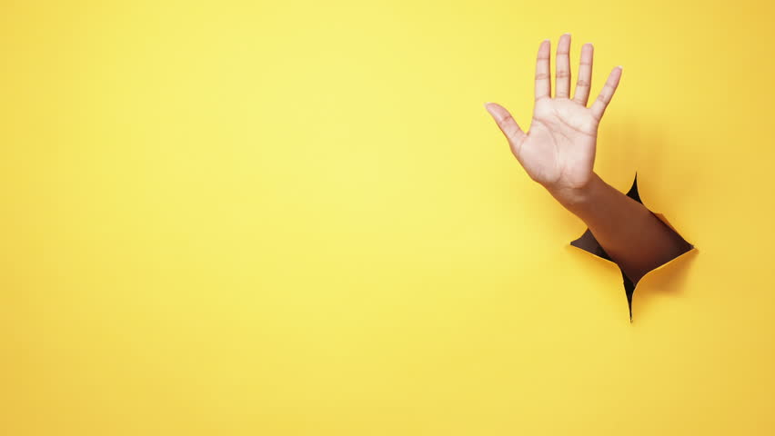 Stop gesture. Rejection no. Restriction signal. Female hand warning with palm sign in yellow breakthrough hole ripped paper wall copy space background. | Shutterstock HD Video #1100414027