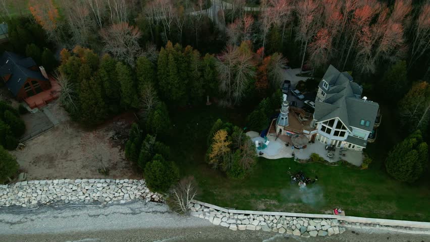 aerial of a blue vacation home from wisconsin USA filmed on autumn. private lighthouse sorounded by green trees.