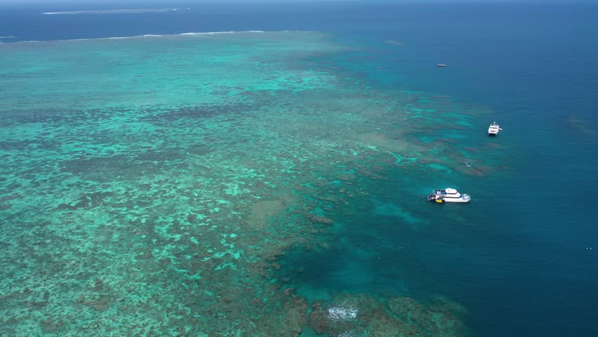 Great Barrier Reef reverse drone shot of boats and coral ecosystem, near Cairns, Queensland, Australia
