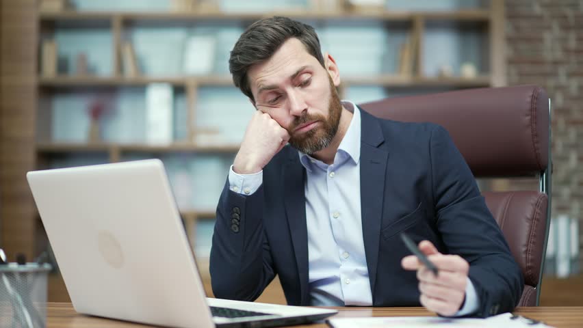 Boring lazy business man employee having long day working on computer with lack of motivation in modern workplace Tired bearded entrepreneur has problems with concentration at desk Procrastination | Shutterstock HD Video #1100419845