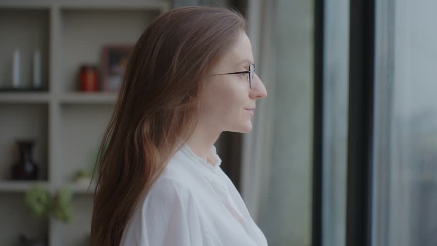 Calm young woman takes off her glasses, taking deep breath of fresh air meditating with eyes closed standing indoor, close up side profile view. Do mental relaxation exercises, feels no stress concept Royalty-Free Stock Footage #1100421313