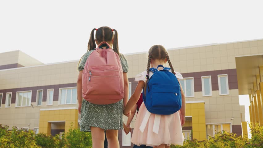 child friends go school with school backpacks. girls schoolgirls holding hands go lesson classroom. teamwork. group children with bags go school building. school students. chidhood dream. Royalty-Free Stock Footage #1100421695
