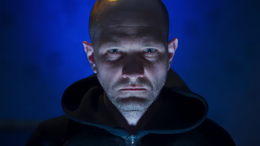 man holding back emotions. closeup portrait of angry man restraining himself in order not to answer something. horror lower light under face man on blue background. terrible portrait. scary male face Royalty-Free Stock Footage #1100424947