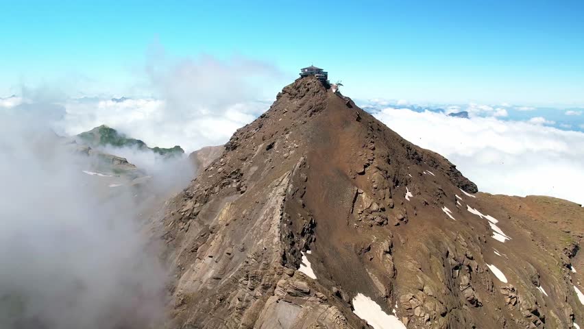 Aerial drone view Schilthorn summit observation deck. Bernese Swiss Alps mountains. Switzerland summer tourism destination.