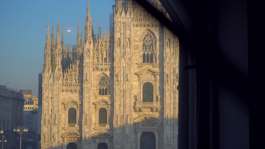 View from the balcony to the square and the cathedral duomo. Luxury apartment or hotel. Romantic appetizer. Evening. Taxi parking in the city center. Sweet life. Dolce Vita Europe Italy Milan 02.2023