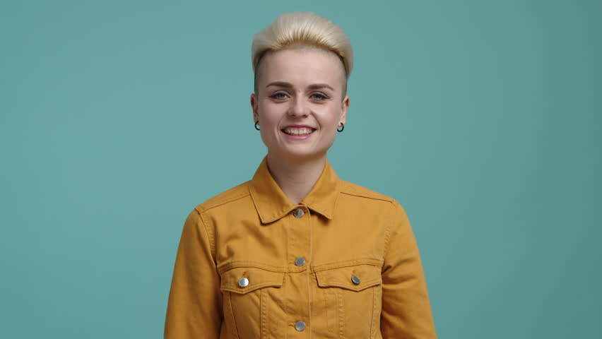 Blonde-haired woman demonstrating her strength while posing at camera. Close-up shot of a girl in her 20s kissing her muscles. High quality 4k footage