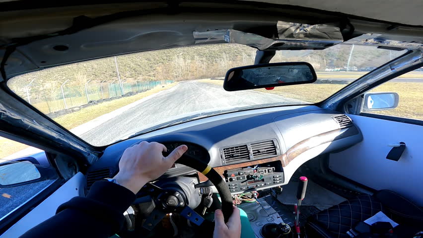 Extreme sport driving for getting adrenaline emotions, driver inside the car drifting on training playground, skilfully switching gearbox, steering wheel and making abrupt turning maneuvers. Car
