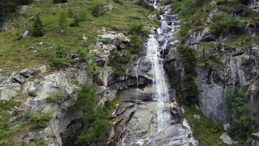 Aerial View Of Waterfall Flowing Through Rocky Mountain Slope In Daytime.