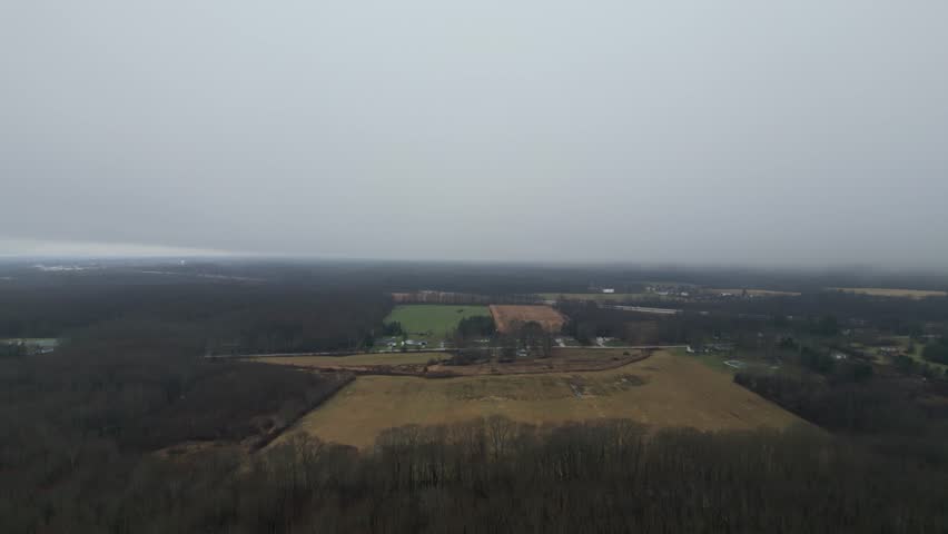An aerial shot of farmland in the middle of the country with a thick heavy fog rolling in.
