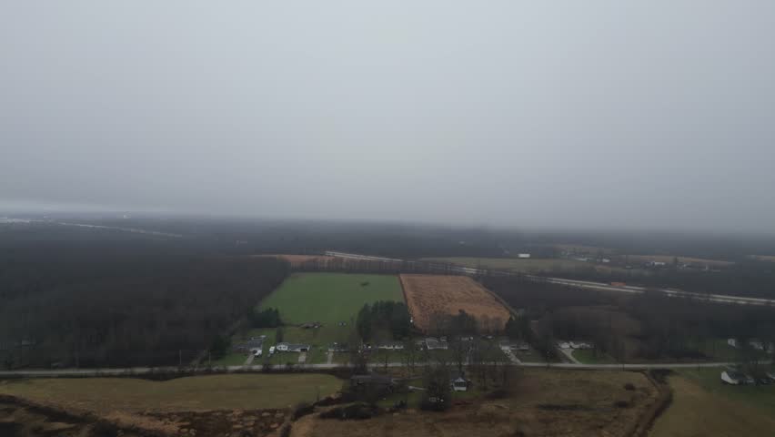 An aerial shot flying over the countryside heading in to a thick heavy fog over I80.